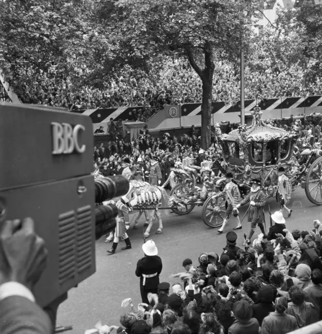 Cameras capture the State Coach on London's Victoria Embankment on its way to Westminster Abbey on the day of the Queen's Coronation on 2 June 1953