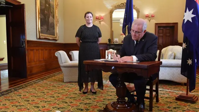 Australian Prime Minister Scott Morrison (R) signs a condolence book following the death of Prince Philip,