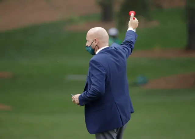 A Masters official sounds the horn to suspend play in round three