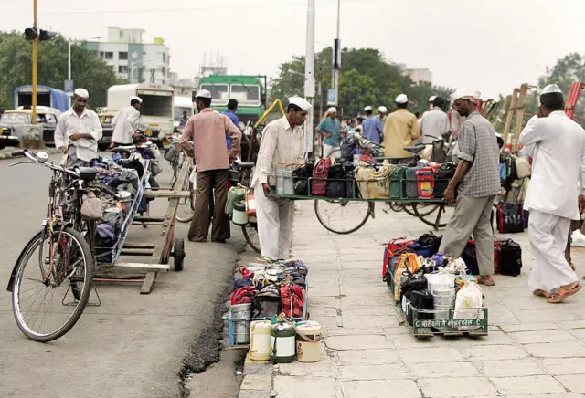 Indian Dabbawalas (delivery men) load tiffin boxes onto their bicycles before delivering them to office workers in Mumbai (July 2006)