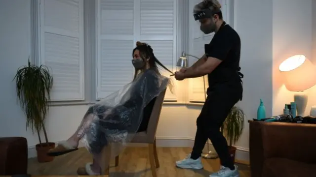 Secret Spa hair stylist Nas Ganev cuts the hair of Amy Pallister, 27, just after midnight at her home in Balham, south London.