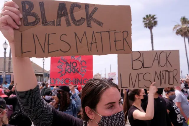 Demonstrators holding signs take part in a Black Lives Matter protest in Huntington Beach, California