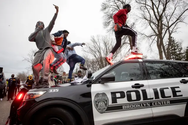 Protesters jump on a police car