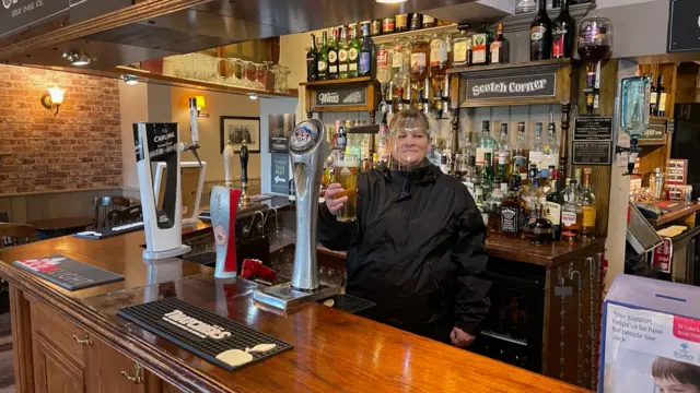 Angie Uren, 53, publican at the Coach and Horses, pulls the first pub's pint