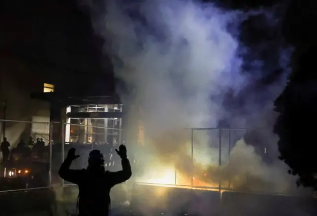 A person puts his hands up while protesters rally outside Brooklyn Center Police Department