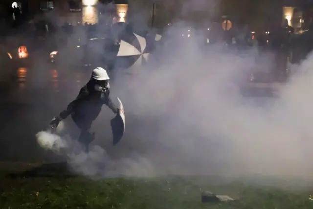 A person holds a tear gas canister while protesters rally outside Brooklyn Center Police Department