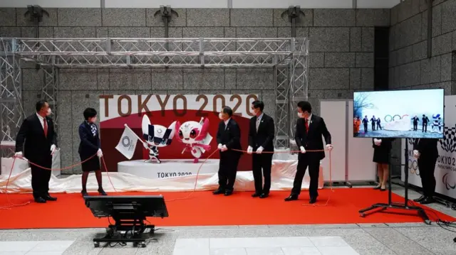 The statues of Miraitowa (C-L) and Someity (C-R), the official mascots for the Tokyo 2020 Olympics and Paralympics, as well as a display of the Olympic symbol at Mt. Takao, (on monitor), are unveiled by officials and guests to mark 100 days before the start of the Tokyo 2020 Olympic Games, at the Tokyo Metropolitan Government building in Tokyo, Japan,