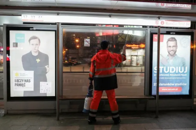 A worker sprays disinfectant as a precaution against the spread of coronavirus at a tram stop in Warsaw, Poland