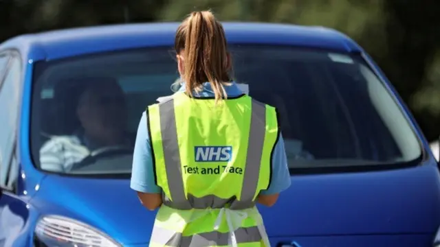 A woman wearing an NHS Test and Trace high-vis jacket