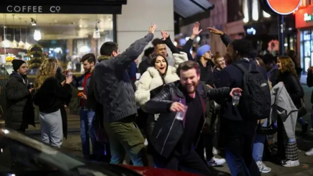 People dancing and laughing in a street in Soho in the evening