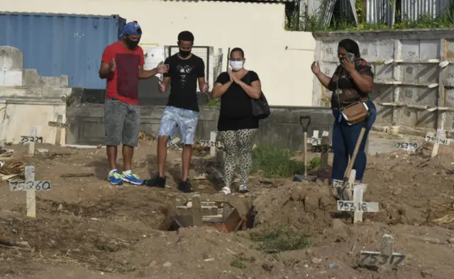 Relatives pray over a grave during burials of Covid19 victims in Rio de Janeiro on 1 April