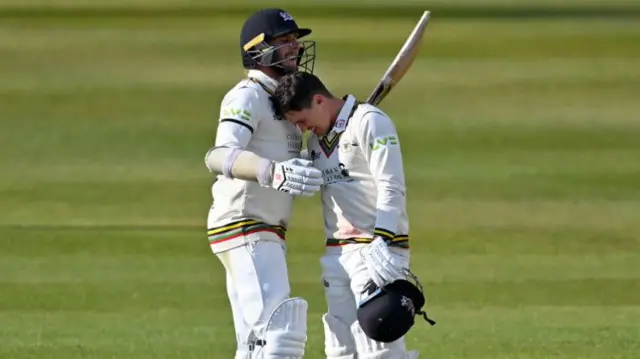 Graeme van Buuren of Gloucestershire (r) celebrates reaching his century with Chris Dent of Gloucestershire