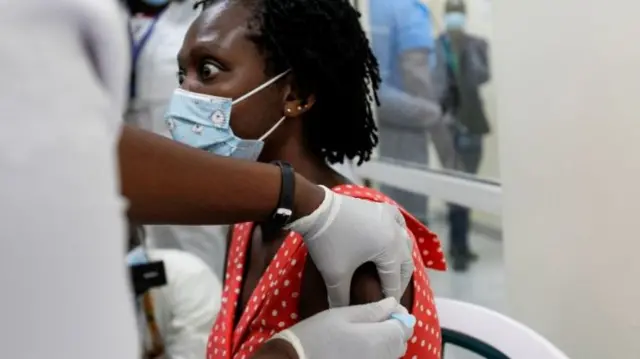 A woman reacts while taking the coronavirus vaccine