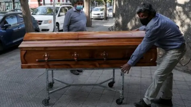 Funeral home workers move a casket outside a morgue at a hospital area in Santiago, Chile