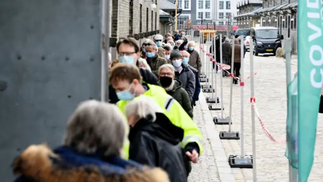 People queue outside the vaccination center in Oksnehallen in Copenhagen, Denmark, on April 12, 2021