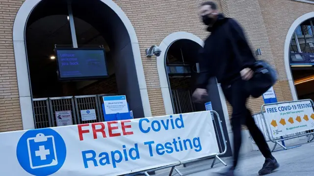 A pedestrian wearing a face covering walks past a sign directing people to a rapid lateral flow Covid-19 testing centre at London Bridge train station in central London on 5 April, 2021.