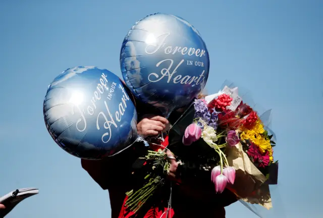 A woman holding flowers and balloons near Windsor castle