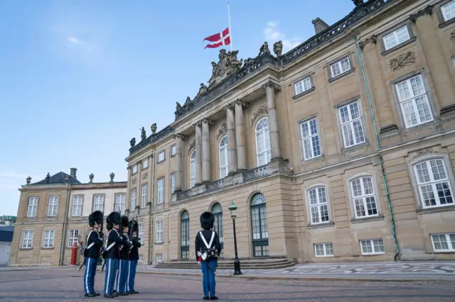 Royal guards stand to attention as the Danish national flag flies at half mast at Amalienborg Palace in Copenhagen