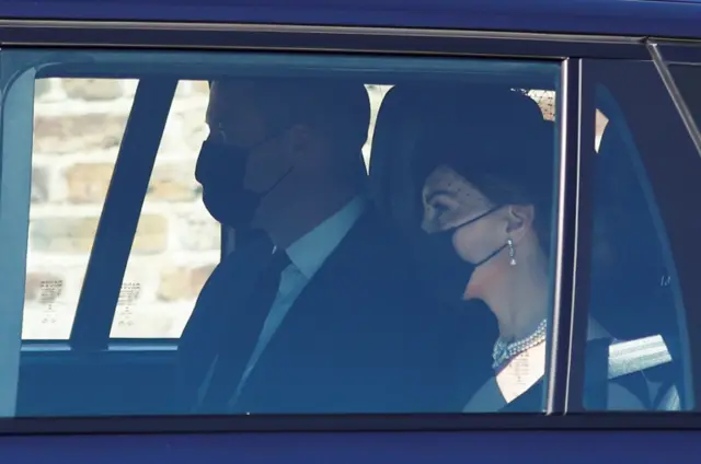 A masked Duke and Duchess of Cambridge, inside a car