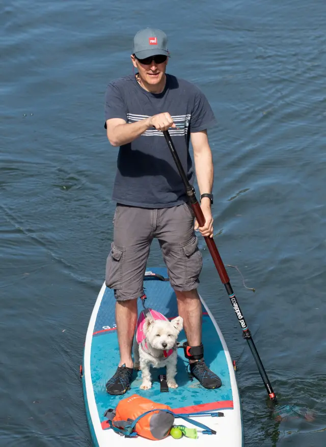 A man and his dog paddleboard along the River Cam in Cambridge