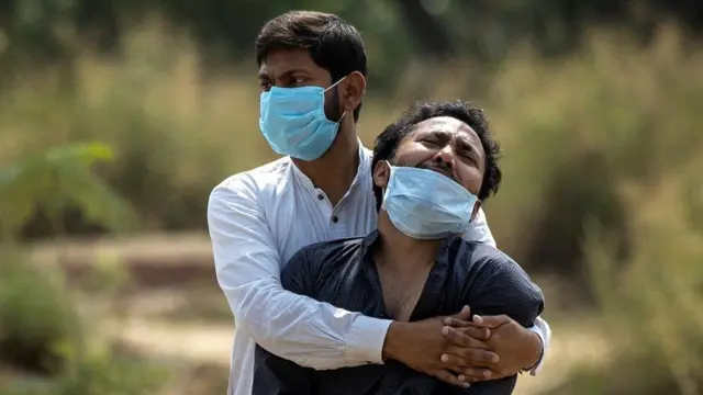 A man weeps as his father is buried in New Delhi, India