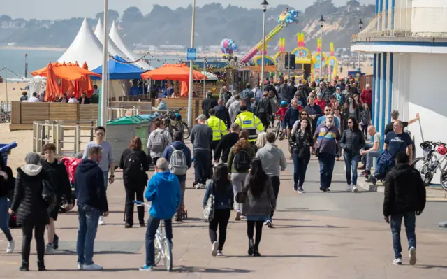 People make their way along the seafront on Bournemouth beach in Dorset