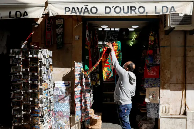 A man hangs football scarves in a Lisbon store on 5 April, the first day of the reopening after a national lockdown