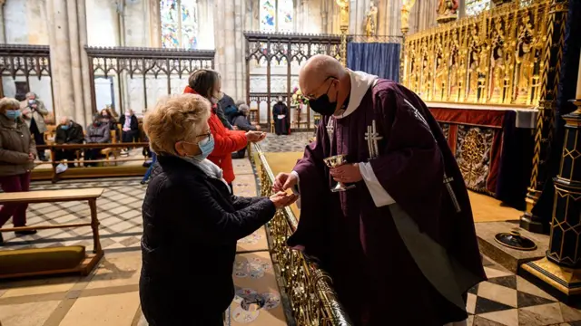 A masked woman receives communion