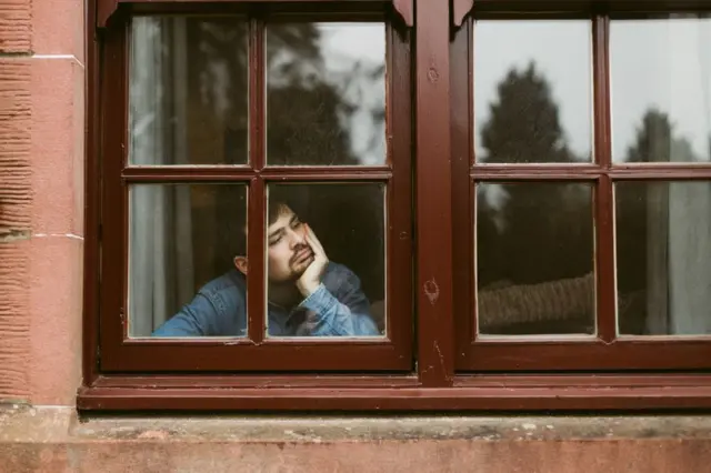 A man sadly looking out of a window