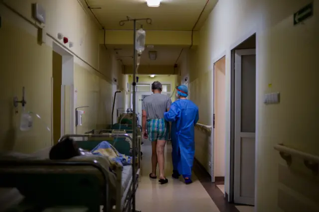 A health worker helps a patient suffering from COVID-19 to walk on the corridor of the General Medicine ward at Bochnia Hospital on April 01, 2021 in Bochnia, Poland.