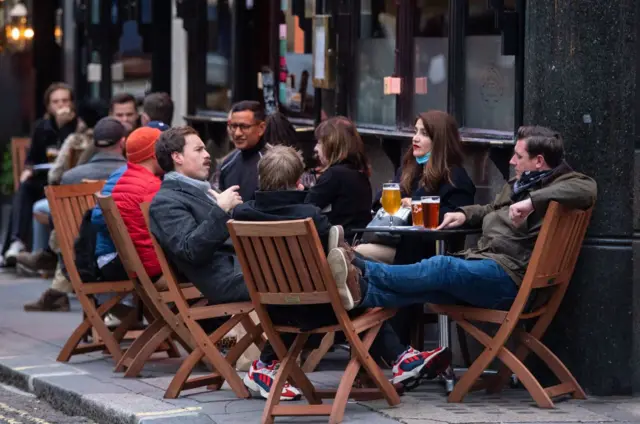 People sit outside a pub in Soho