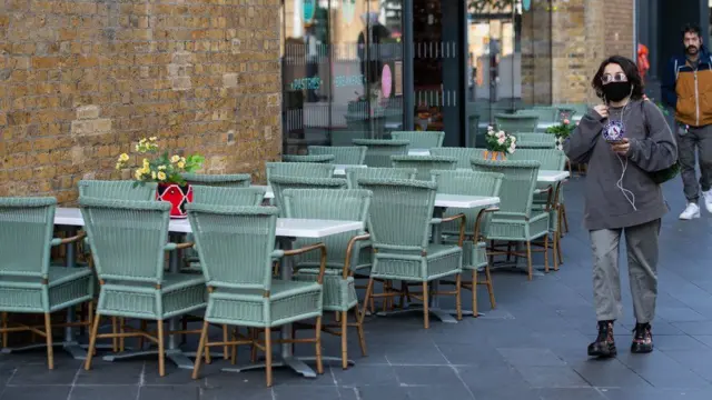 A masked woman walks past a restaurant