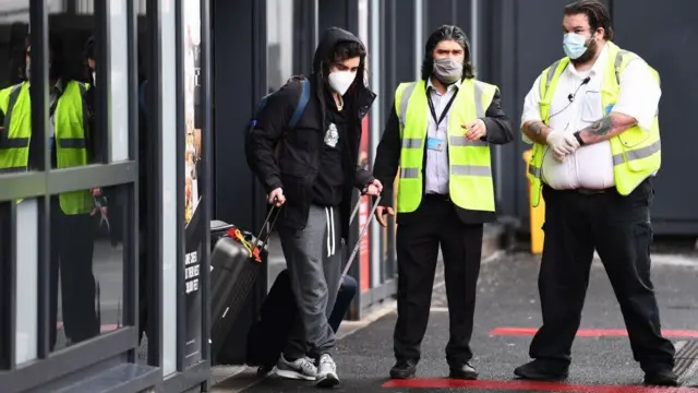 A person leaving an airport wearing a mask