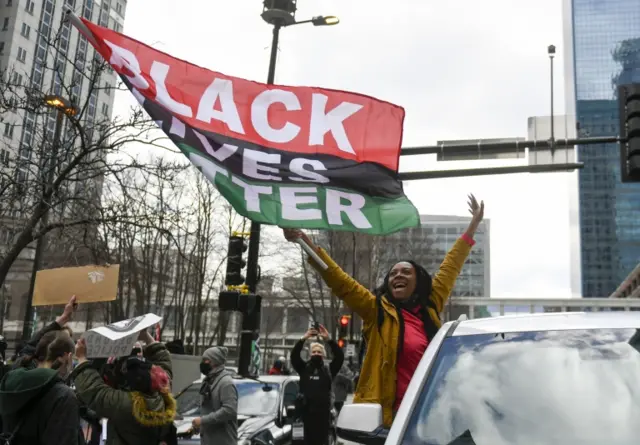 Woman with a flag reading "Black Lives Matter"