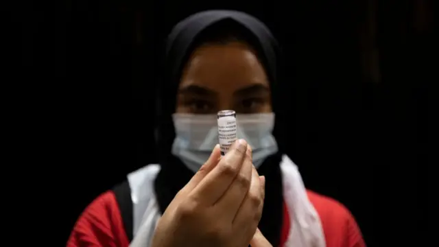 A nurse prepares a vaccine at a mosque