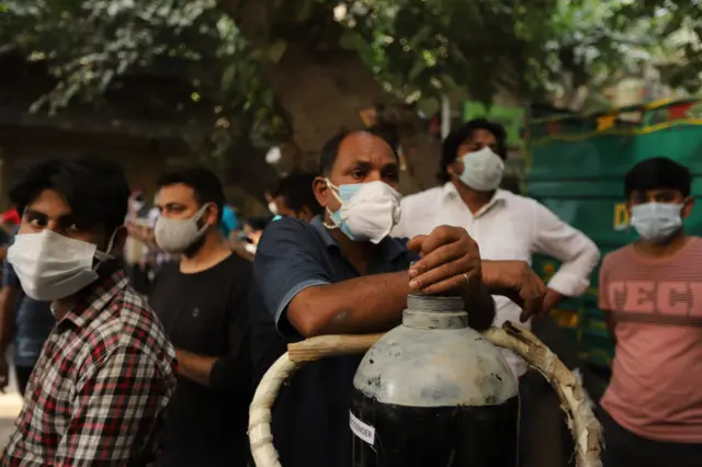 Family members of Covid-19 infected patients stand in a queue with empty oxygen cylinders outside the oxygen filling center, in New Delhi, India