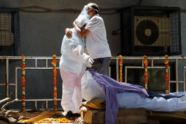 Here two Delhi residents wearing PPE mourn their relative