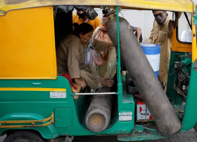 Aminbanu Memon wearing an oxygen mask sits in an autorickshaw waiting to enter hospital for treatment