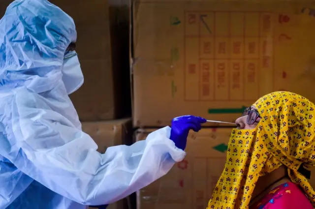 A medical representative (L) collects a swab sample from a resident for the COVID-19 coronavirus test in a residential area in Mumbai on September 7, 2020