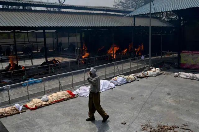 A man walks past bodies of Covid-19 coronavirus victims lined up before cremation in New Delhi