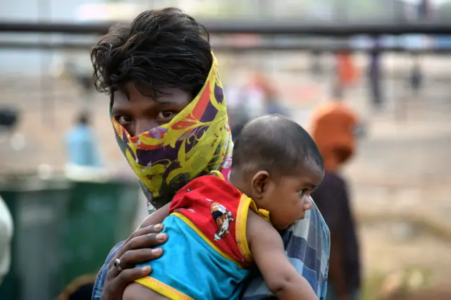 A man wearing a mask and carrying a child