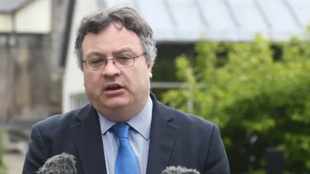 Stephen Farry standing outside and speaking into a microphone