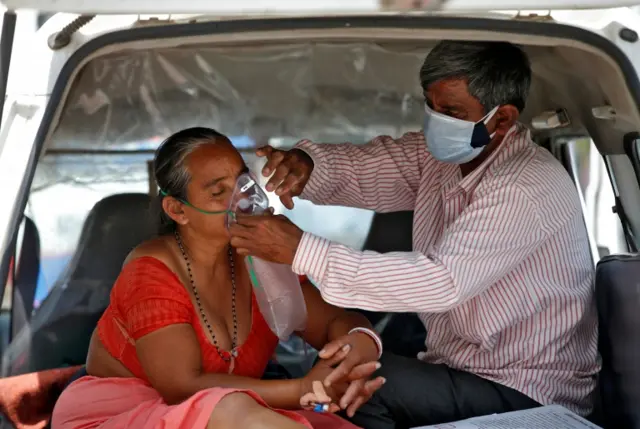 A man adjusting his wife's oxygen mask in a car