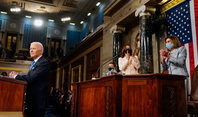 Biden, Harris and Pelosi stand at the dais