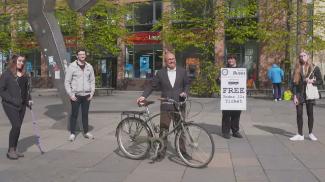 Patrick Harvie holds a bicycle in the middle of four young people