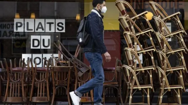 A man walks by an empty cafe in Paris