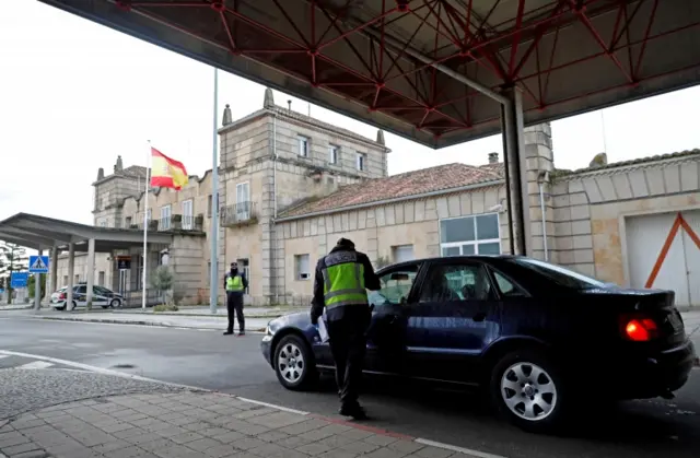 A Spanish police officer checks a car at the border between Portugal and Spain, following an order from the Spanish government to set up controls at its land borders over coronavirus,