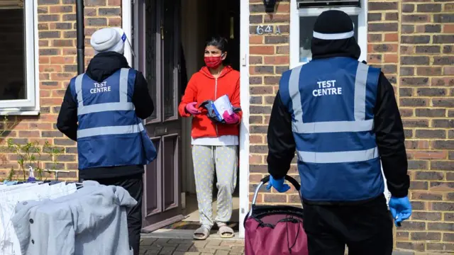 Two test centre workers visit a woman at home