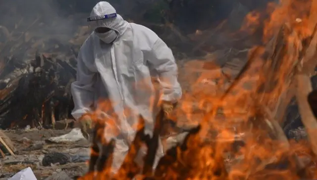 A family member, wearing PPE, performs the last rites for Covid-19 victims