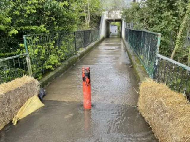 Flooded road with hay bales